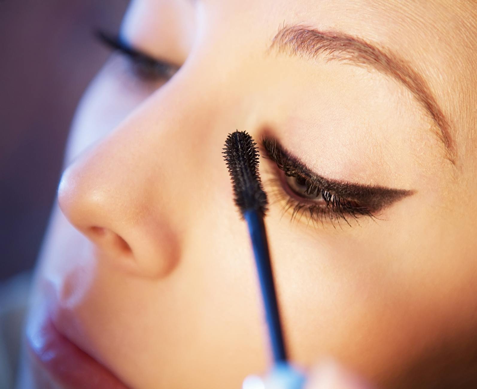 beauty trends and tips - Detailed close-up of a woman applying mascara to enhance her eye makeup look.