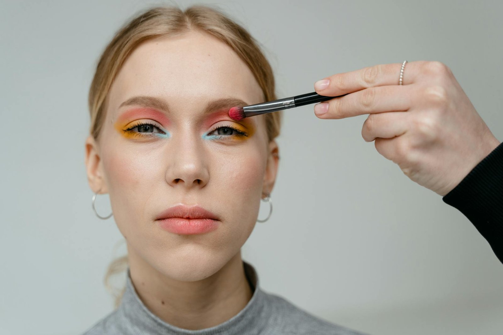beauty trends and tips - Close-up portrait of a woman with vibrant eyeshadow applied with a brush.