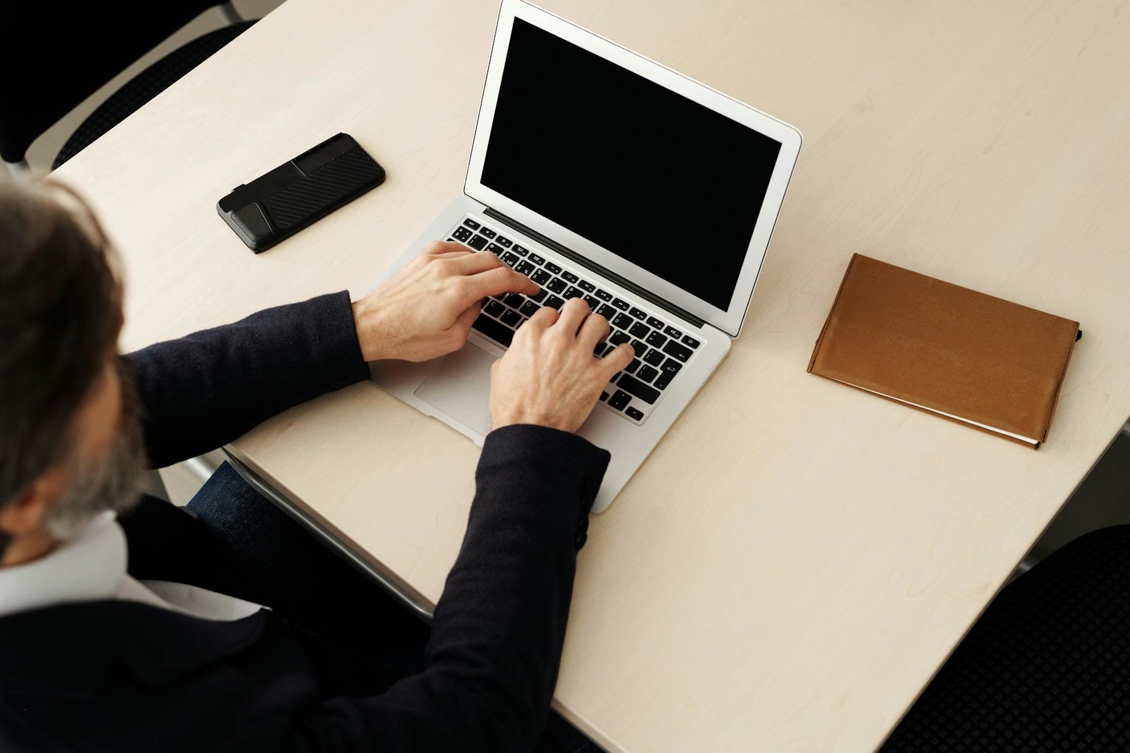 best gadgets for entrepreneurs - A businessman typing on a laptop at a desk, using technology to complete tasks.