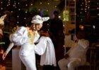 celebrity fashion moments - Bride in white dress gracefully dancing at a vibrant wedding celebration with joyful guests.