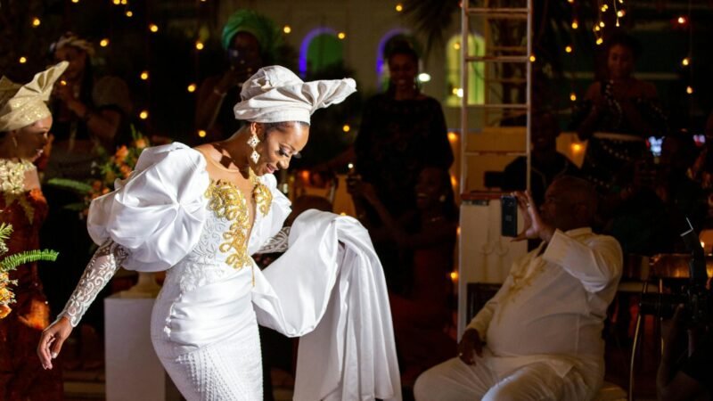celebrity fashion moments - Bride in white dress gracefully dancing at a vibrant wedding celebration with joyful guests.