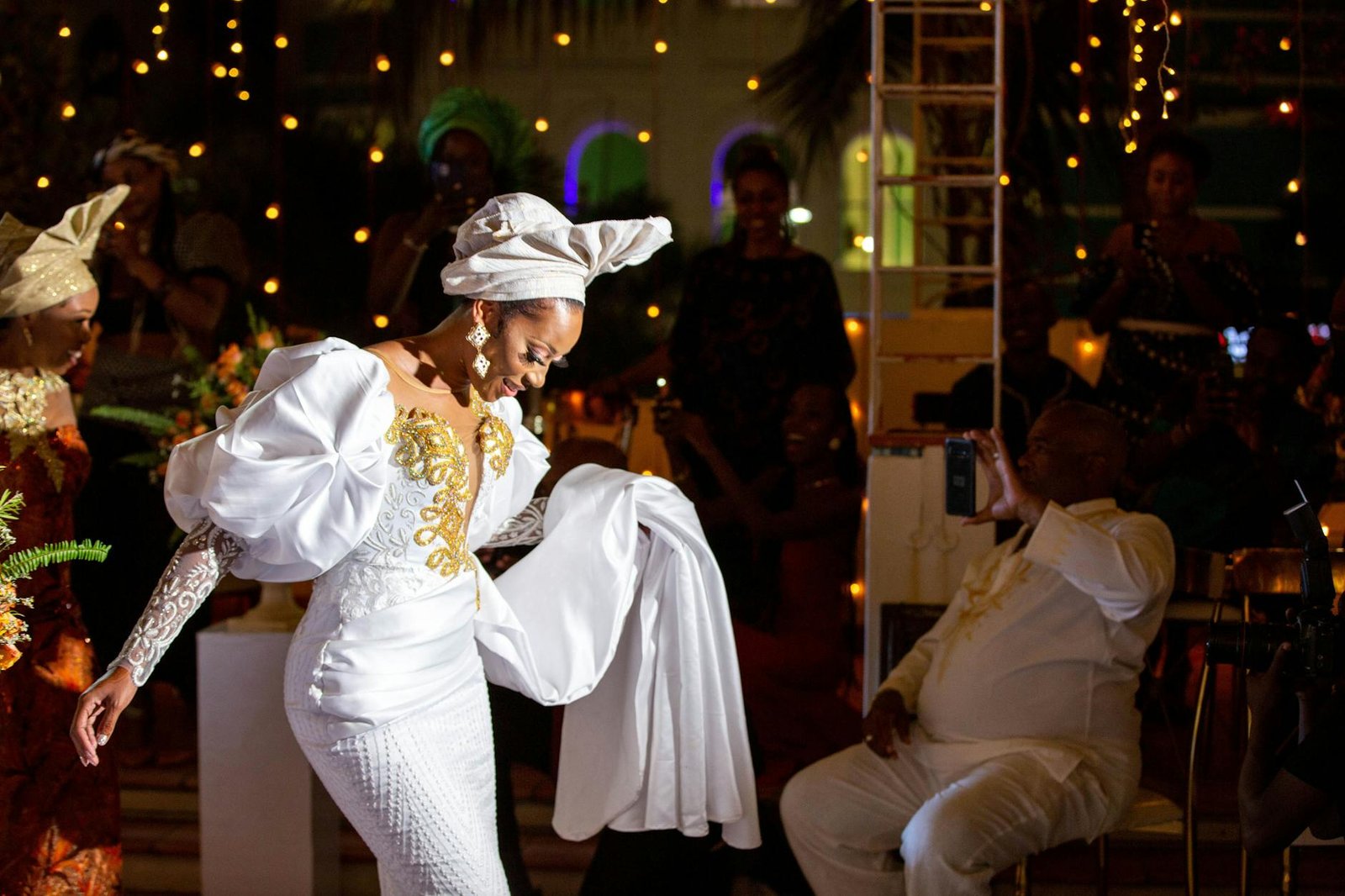 celebrity fashion moments - Bride in white dress gracefully dancing at a vibrant wedding celebration with joyful guests.