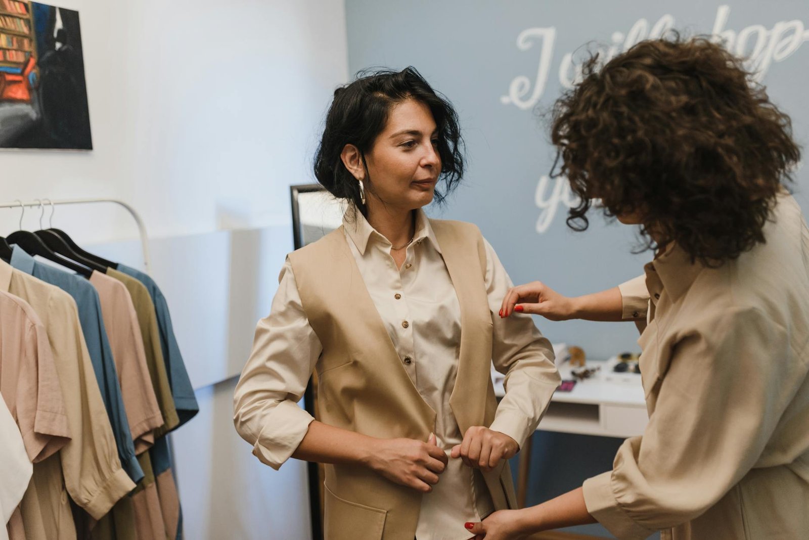 fashion career guides - A fashion stylist helps a woman adjust her outfit in a trendy boutique.