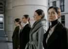fashion career guides - Four professional women in elegant coats walking in an urban setting, showcasing diversity and style.