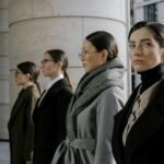 fashion career guides - Four professional women in elegant coats walking in an urban setting, showcasing diversity and style.