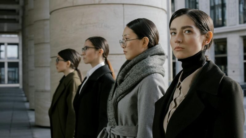 fashion career guides - Four professional women in elegant coats walking in an urban setting, showcasing diversity and style.