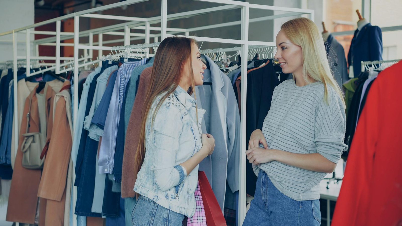 fashion trends and career advice - Two women chatting among clothing racks in a stylish fashion store, sharing shopping advice.