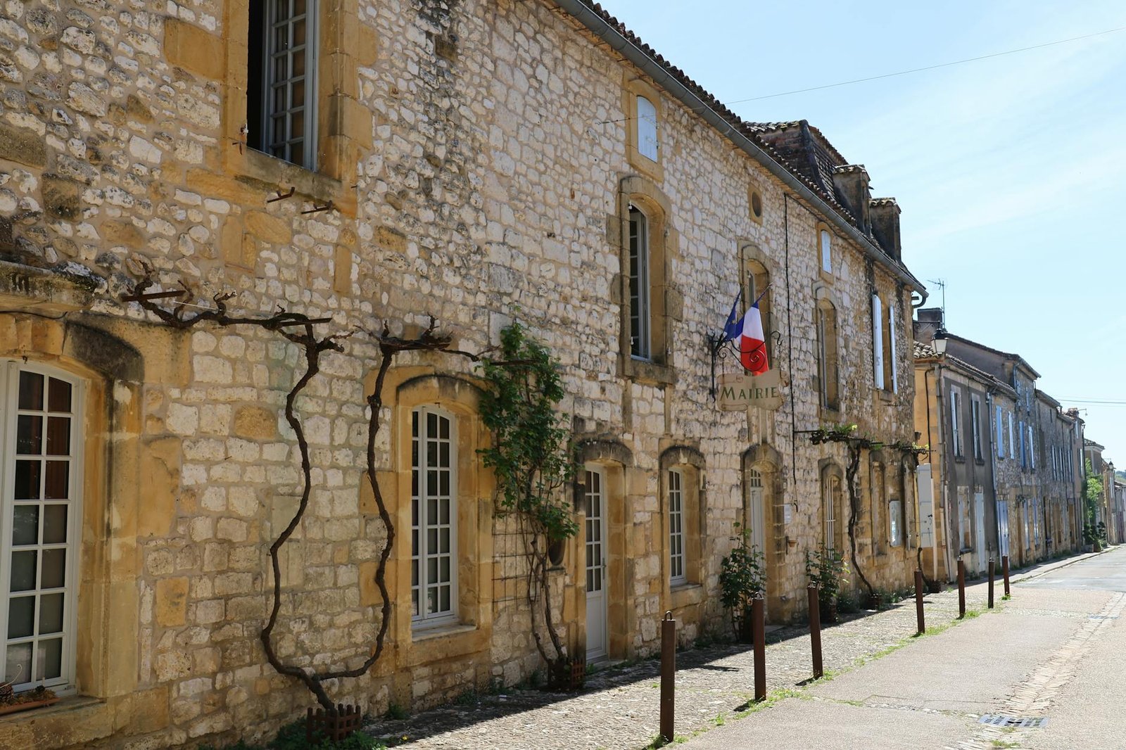 french style inspiration - Picturesque view of a historic street in a French village with rustic stone buildings and French flags.