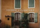 french style inspiration - Rustic French building facade with green shutters and climbing plants in Provence.