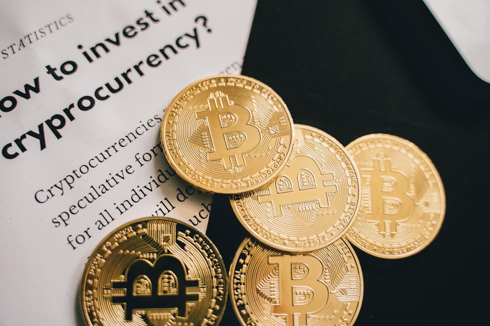 how to invest in crypto - Close-up of Bitcoin coins alongside an investment guide in cryptocurrency.