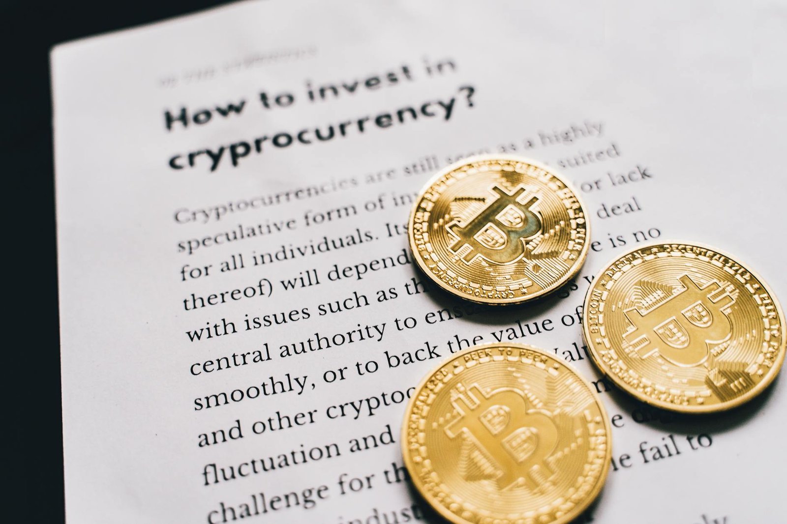 how to invest in crypto - Close-up of Bitcoin coins on an investment guide paper.