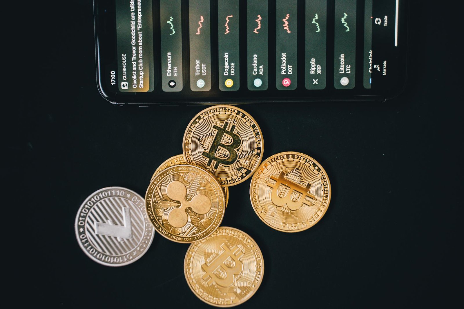 how to invest in crypto - Close-up of various cryptocurrencies and a smartphone showing market trends.