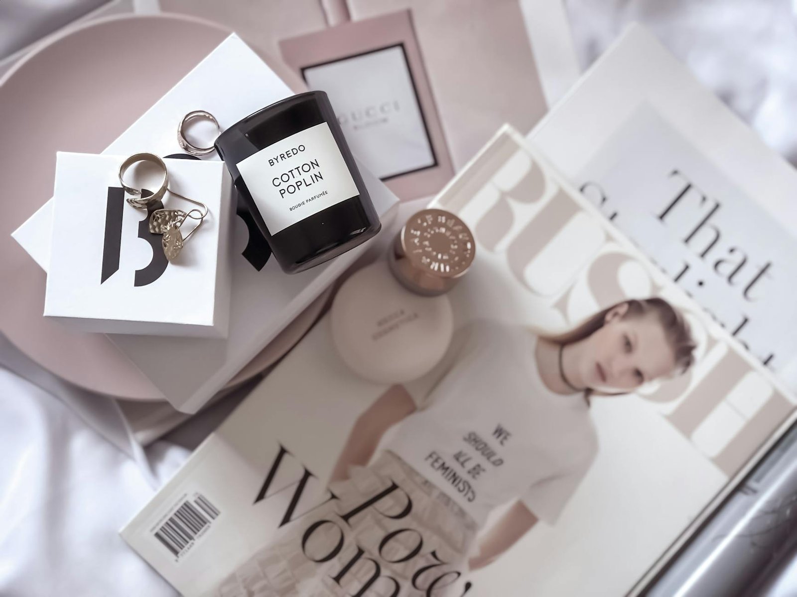luxury lifestyle fashion trends - Stylish flat lay featuring fashion magazines, Byredo candle, and accessories.