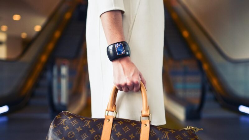luxury lifestyle fashion trends - Chic woman with luxury handbag and bracelet in modern shopping environment.