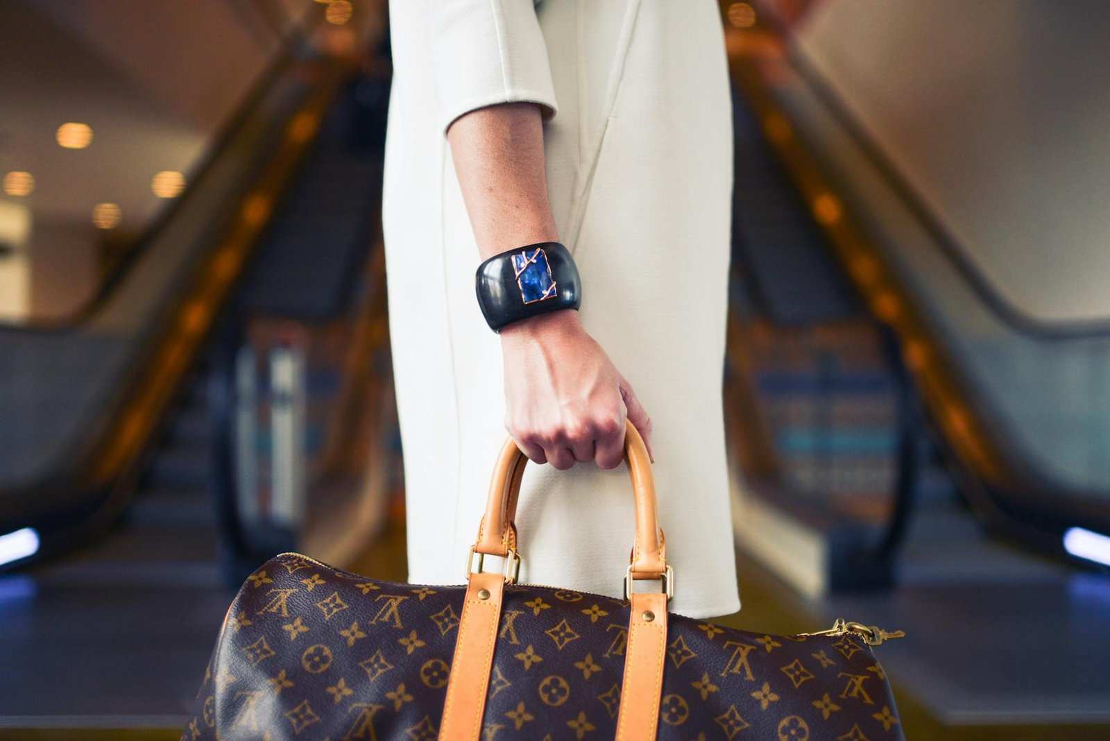 luxury lifestyle fashion trends - Chic woman with luxury handbag and bracelet in modern shopping environment.