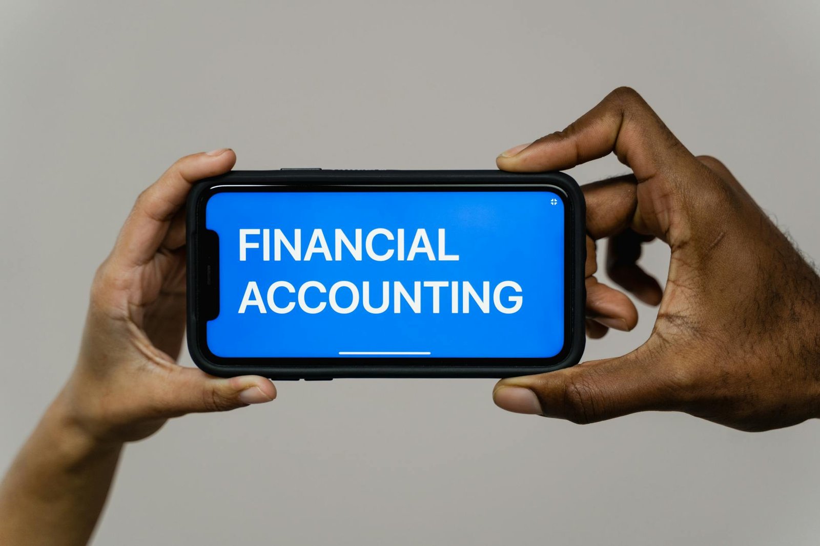 What Is Fintechzoom Image 6694477 what is fintechzoom - Close-up of hands holding smartphone displaying 'Financial Accounting'.