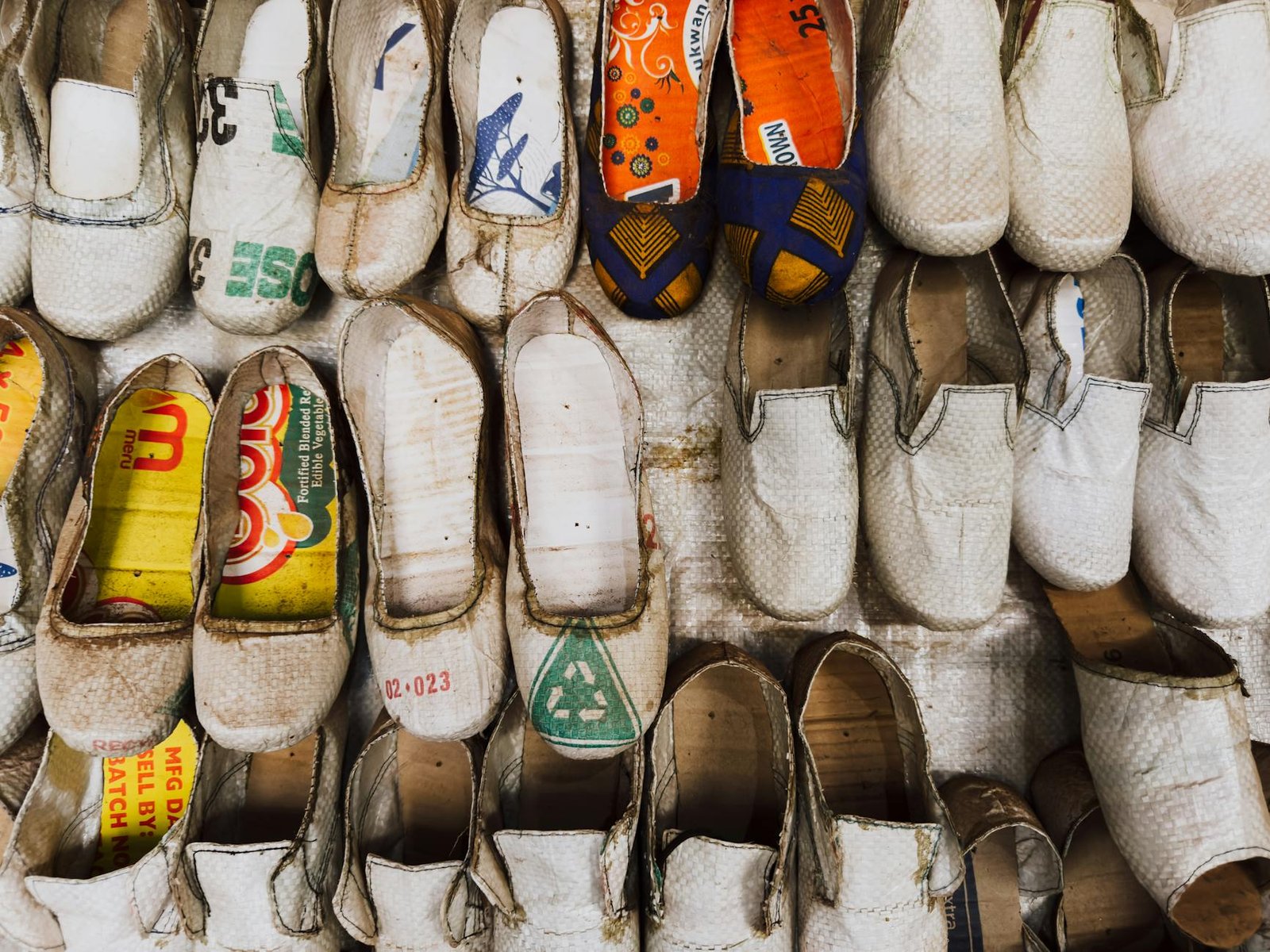 what is sustainable fashion - Unique shoes crafted from recycled materials in a Ugandan market display.