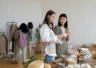 what is sustainable fashion - Four women browsing clothes and items at an indoor swap party, focused on sustainable living.